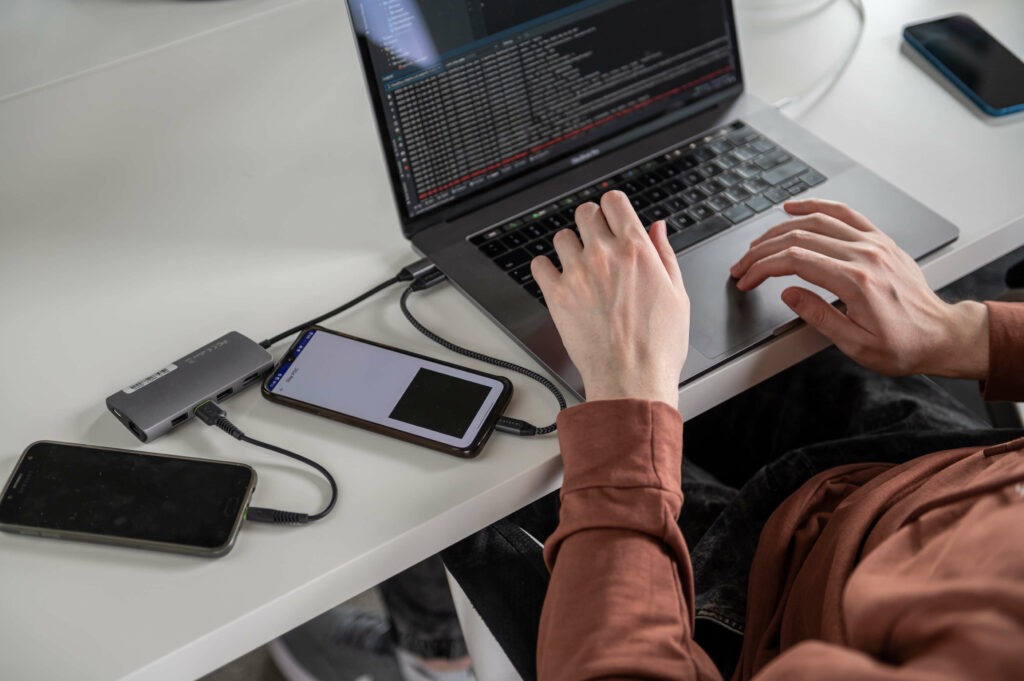 Developer testing an app on a laptop with connected phones Developer testing an app on a laptop with connected phones